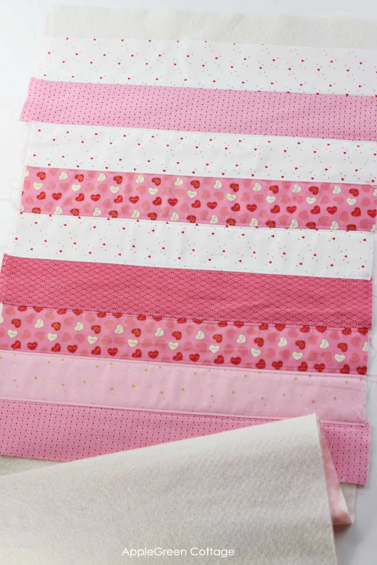 unfinishedtable runner in shades of pink, red, and white strips of fabric