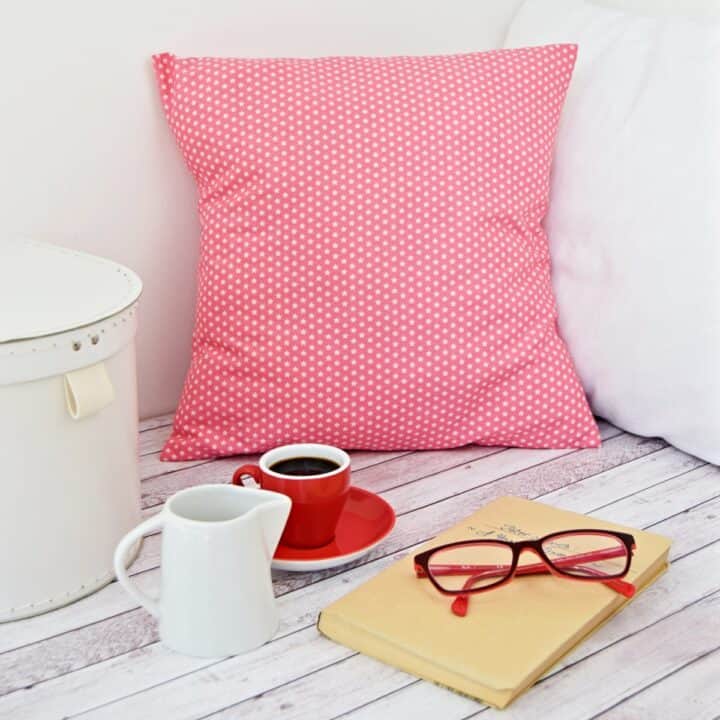 a printed cotton fabric pillow cover in a reading nook next to reading glasses, a cup of espresso, and a white box