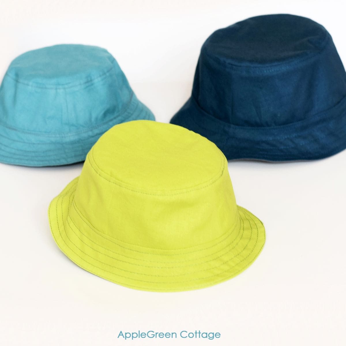 three finished handmade bucket hats in lime green, light teal and navy fabric