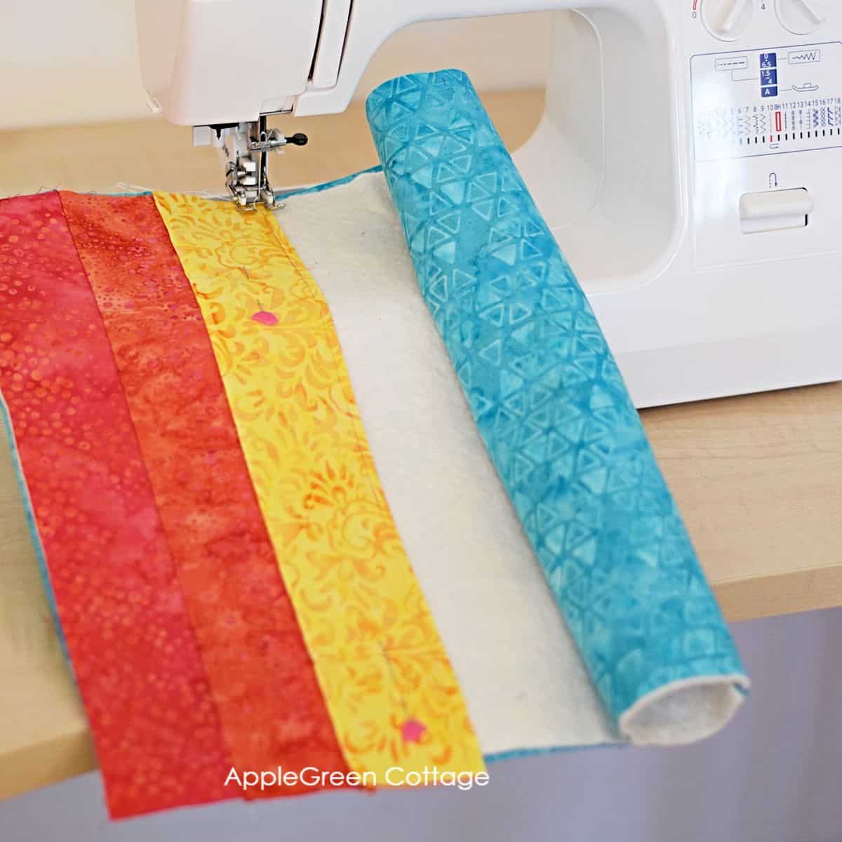 quiltign cotton strips being pieced together on a domestic sewing machine