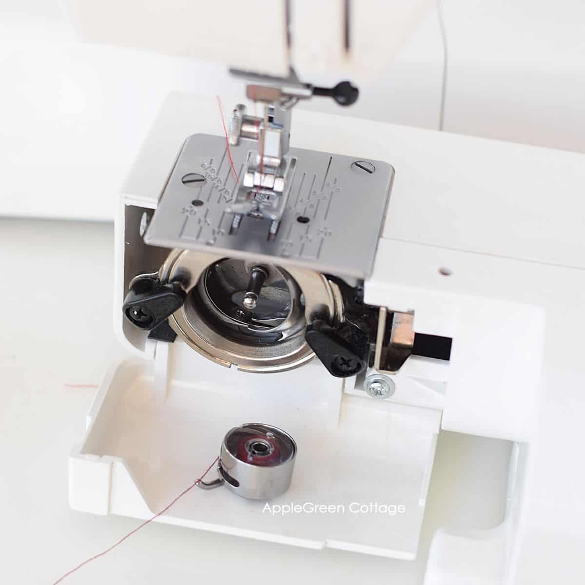 a closeup of a vertical shuttle hook system on a sewing machine with a front-load bobbin case