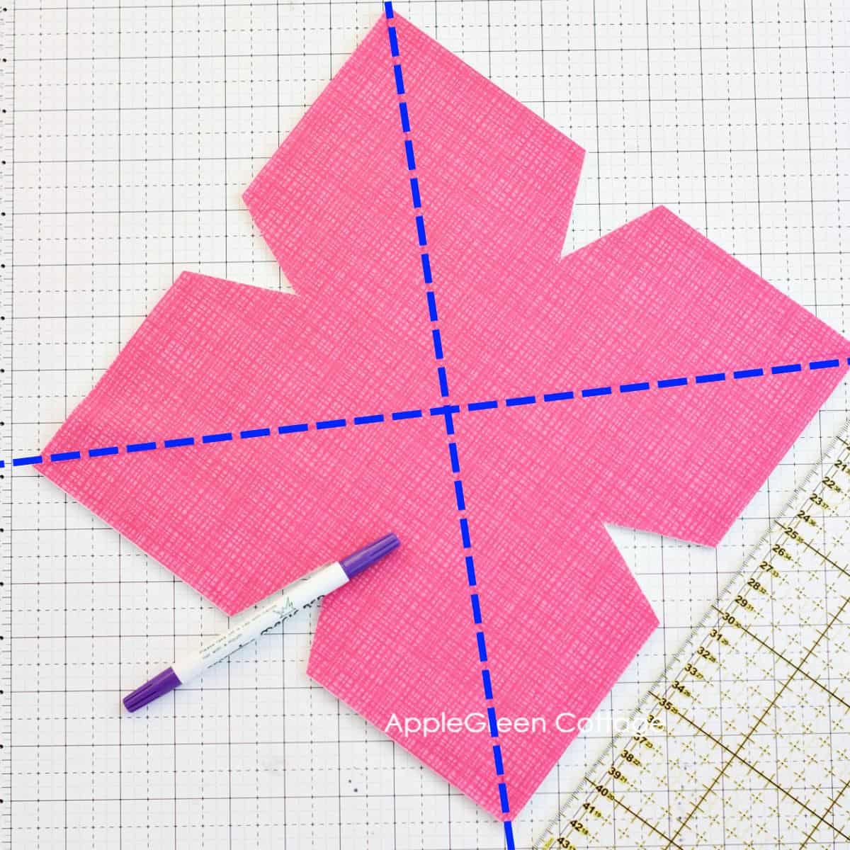 a fabric markeing pen next to a quilting ruler , with markings on fabric to quilt