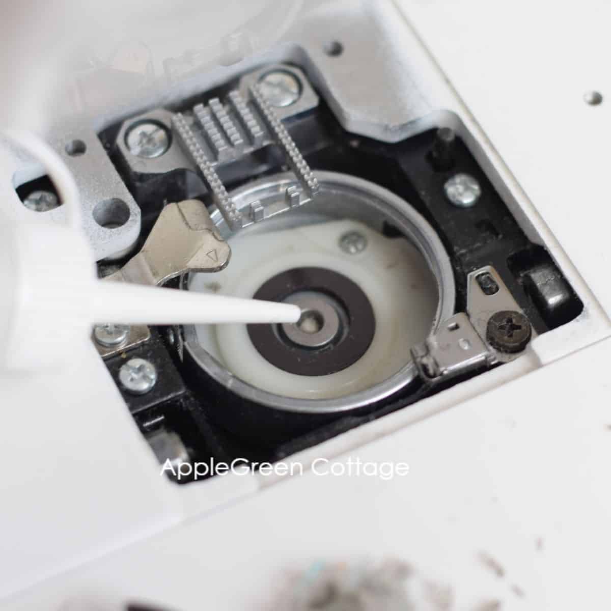 closeup of a bobbin area on a janome mechanical sewing machine with the wick in the centre which is marked as the oiling spot