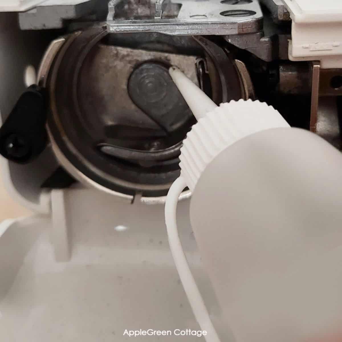 oiling the hand of the shuttle driver on a vertical, oscillating bobbin of a sewing machine