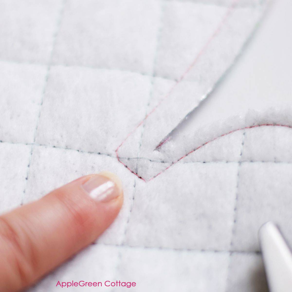 quilted layer of the insulating batting, with a seam visible and a finger pointing to it