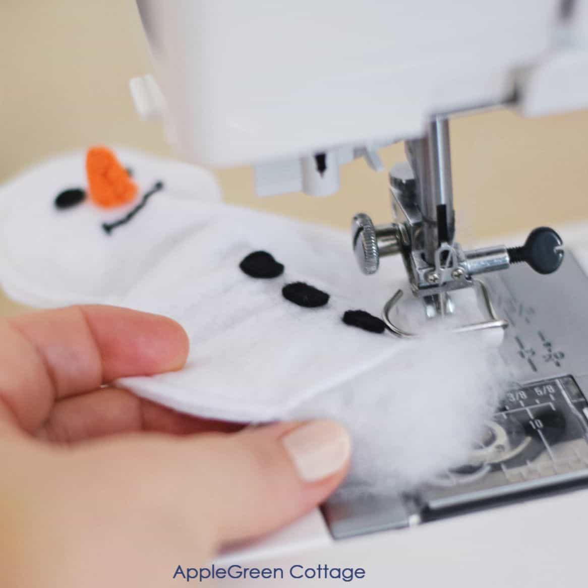 closeup of a sewing machine with a half-sewn felt snowman and some toy stuffing