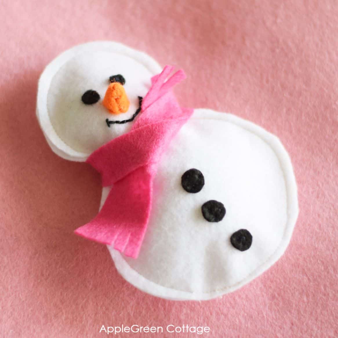 a tiny felt scarf tucked around a felt snowman figure