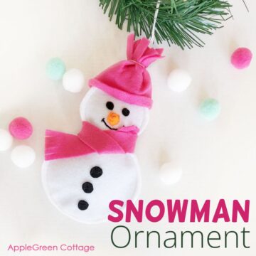 finished felt snowman ornament with white and pink felt on a flatlay