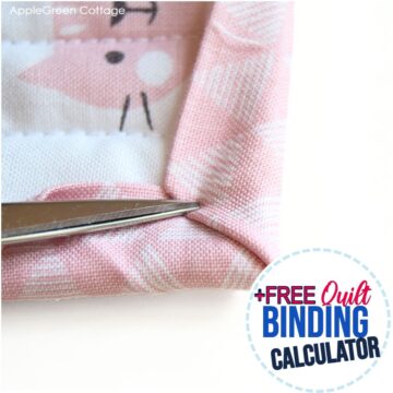 Close-up of a quilt binding being sewn with a pair of scissors adjusting the fabric. The binding features a soft pink print, and the text overlay highlights "FREE Quilt Binding Calculator".