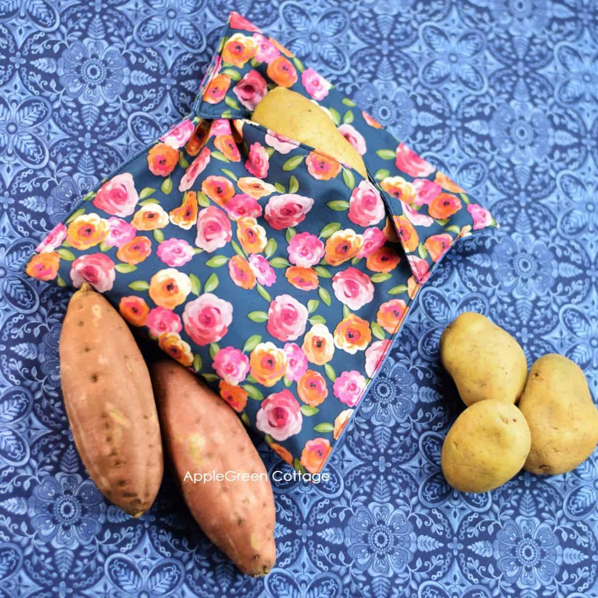 a fabric microwave potato bag filled with russet potatoes and next to sweet potatoes, waiting to be baked in a microwave