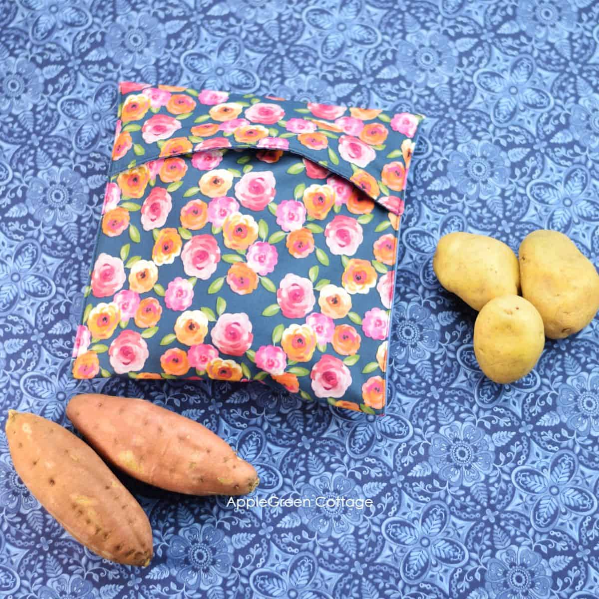 a finished fabric potato bag for the microvawe filled with potatoes to be cooked, placed on a blue fabric table cloth