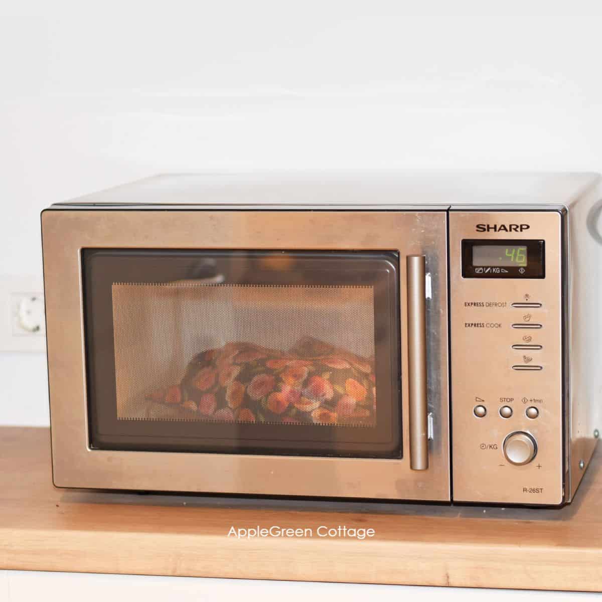microwave on a kitchen counter with potatoes baking in a fabric microwave potato bag