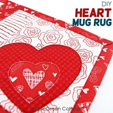 a homemade fabric quilted mug rug with a heart shape in red and white fabric