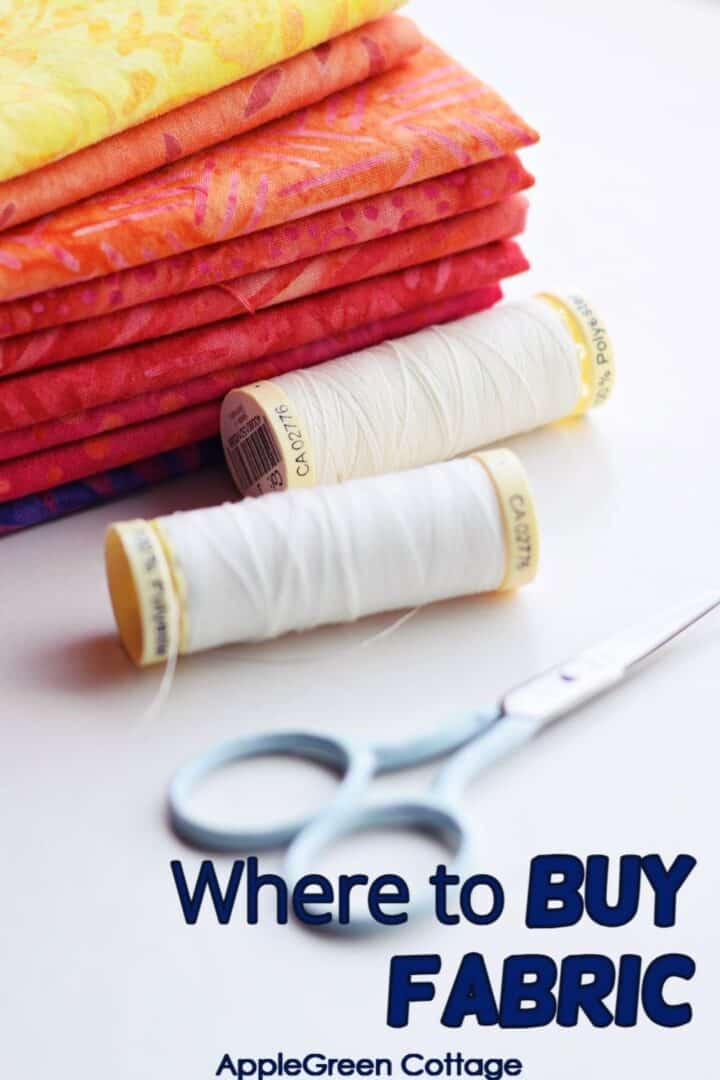 Stacked batik fabrics with white thread spools and scissors for a fabric shopping guide.