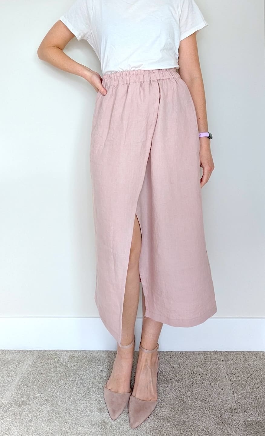 a woman wearing a light maxi faux wrap-style skirt in light pink linen with an elastic waist