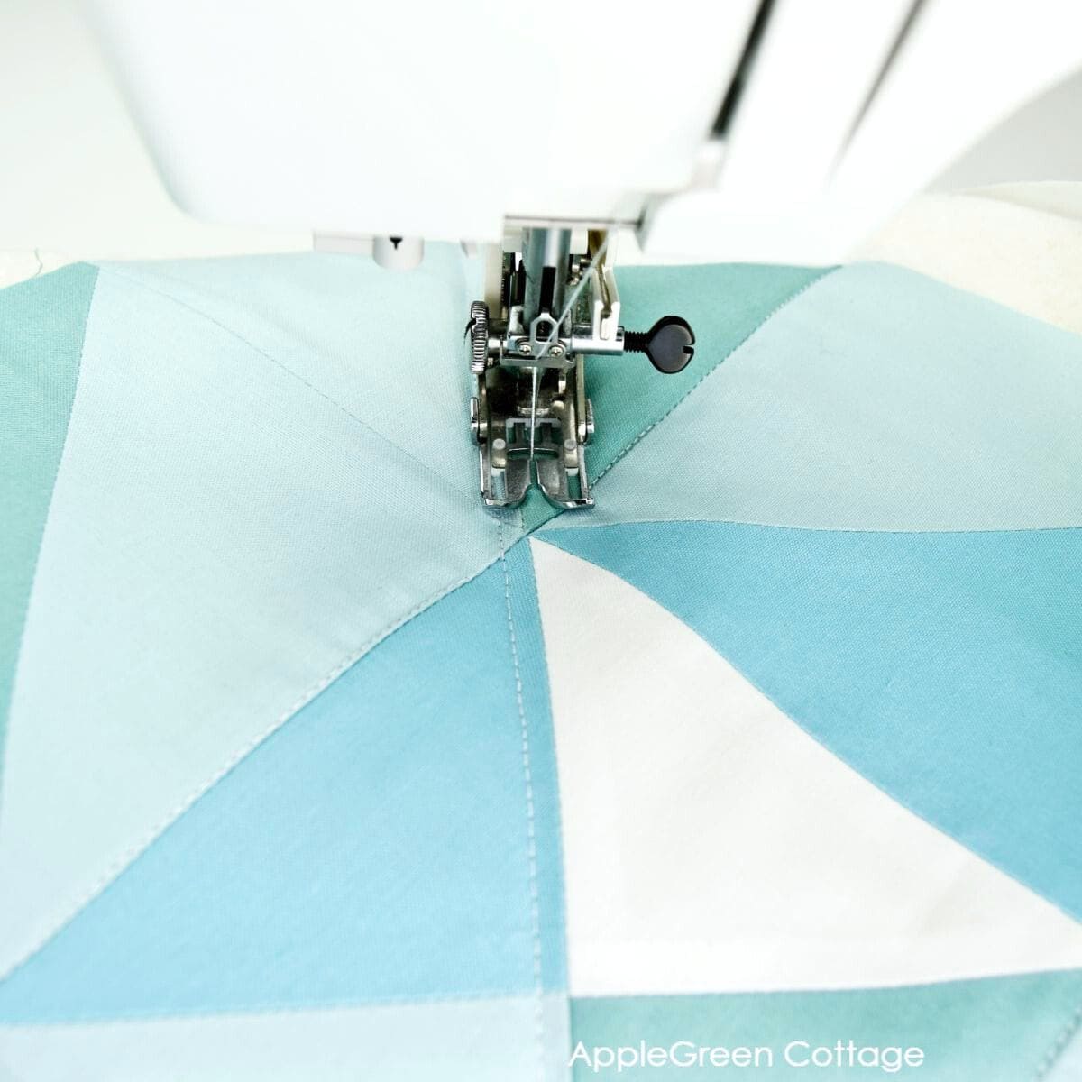 a closeup of a pieced quilt being quilted using a walking foot on a domestic sewing machine
