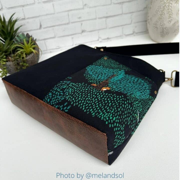 a handmade bag with a front exterior pocket, sewn with black canvas and a beautiful designer cotton print, and a brown leather bottom