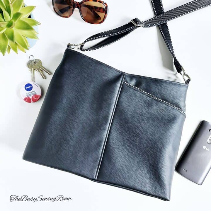 a handmade bag with a front exterior pocket, sewn with with black faux leather, next to sunglasses, keys, and a lip balm