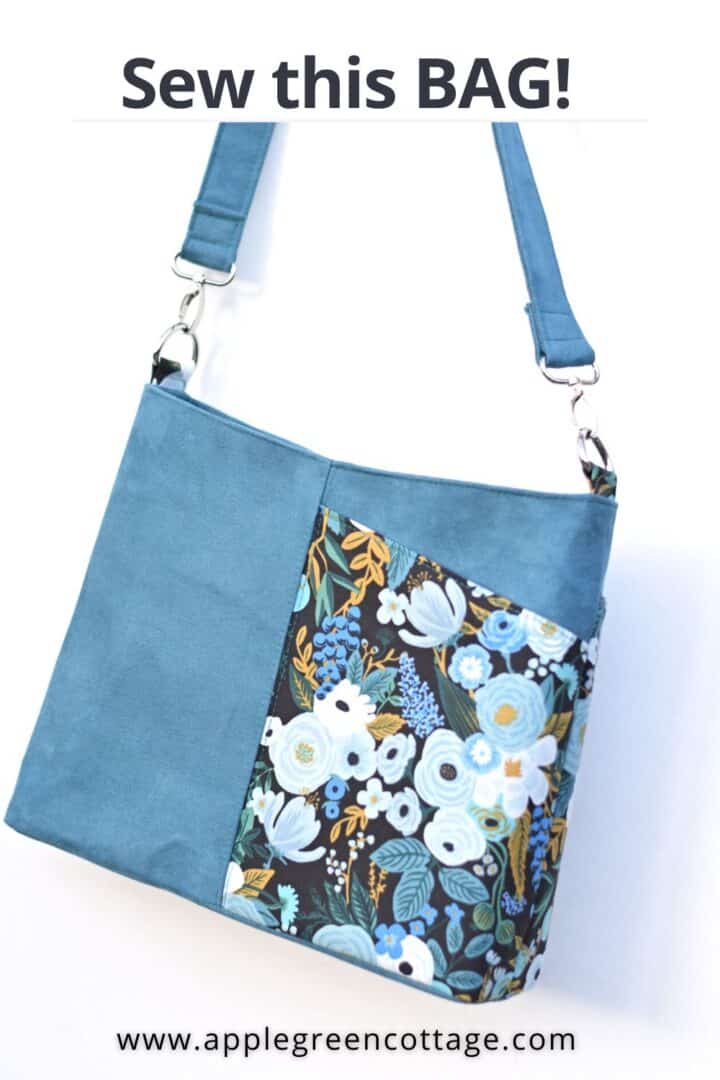 a beautiful handmadce shoulder bag in blue faux suede and floral quilting cotton in blue, hanging from a white wall