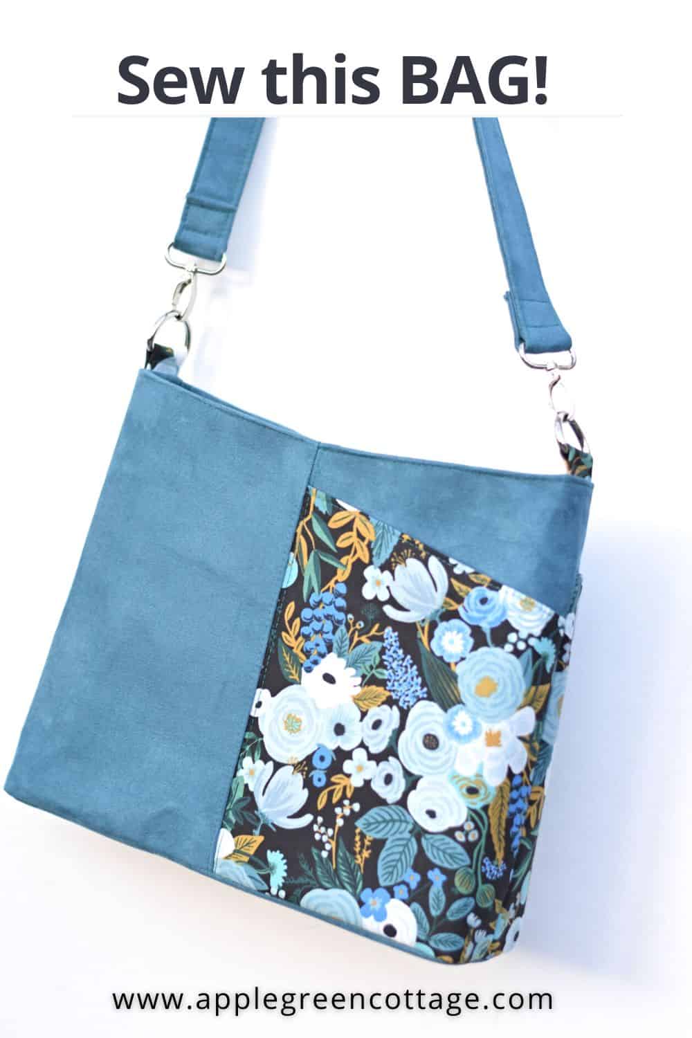 a beautiful handmade shoulder bag in blue faux suede and floral quilting cotton in blue, hanging from a white wall