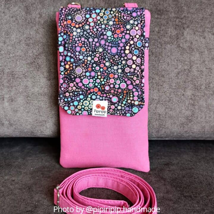 a handmade pink fabric cell phone bag with a flap and a crossbody strap