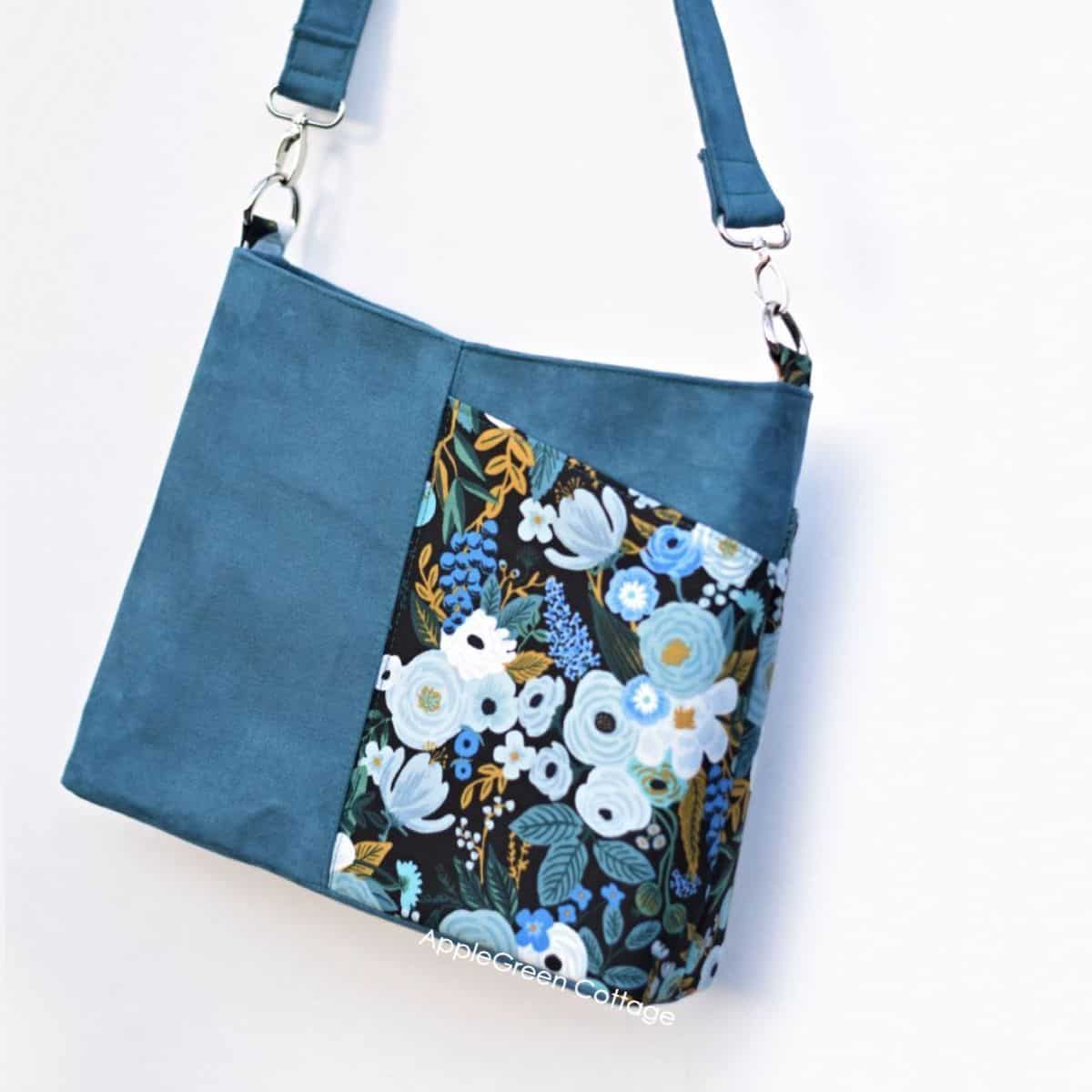a finished shoulder handbag made with blue faux suede and a riflepaper print
