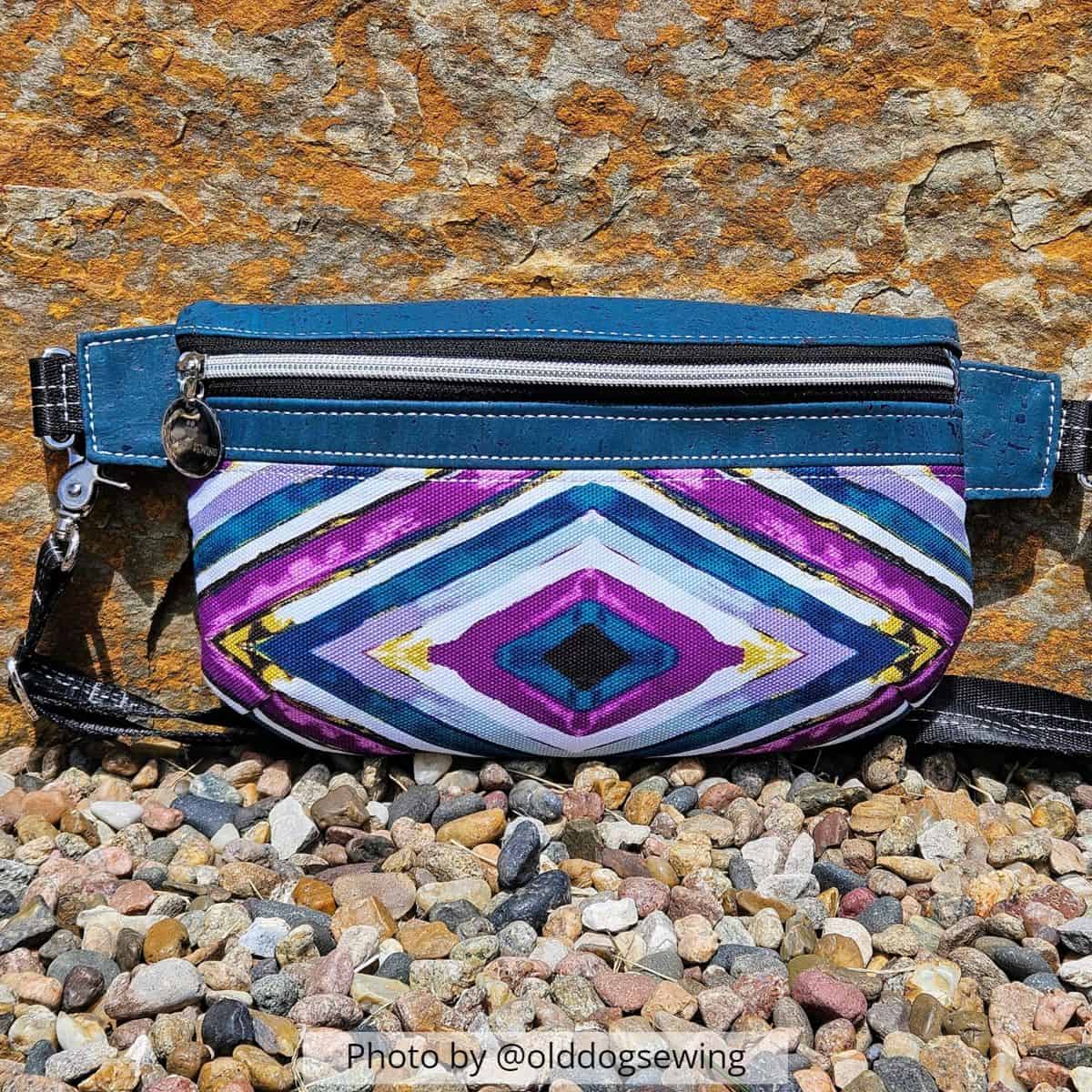 a finished hip bag sewin with blue cork and a vinyl in brigth colors, in front of a large brown rock