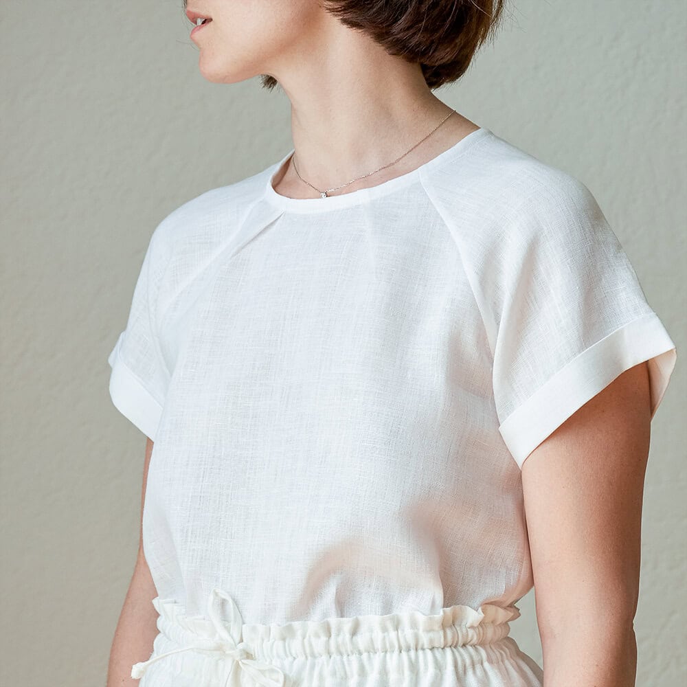 a woman wearing a short-sleeved womens top sewn with white linen