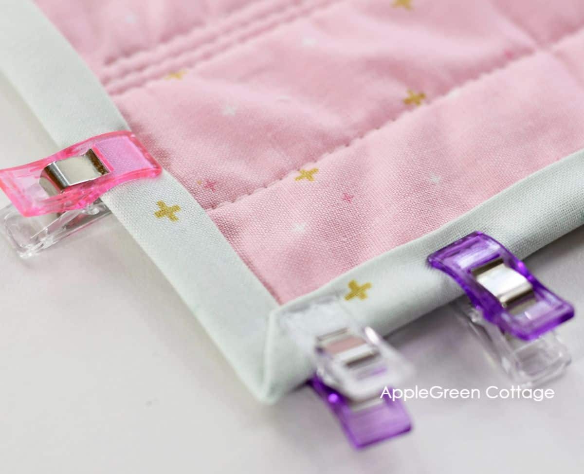 small sewing clips holding the binding on a quilt in place