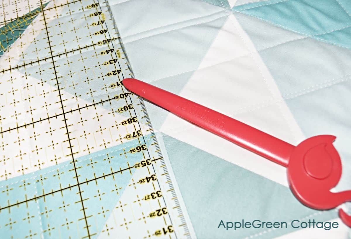 point turner and creaser tool on a pieced quilt next to a quilting ruler