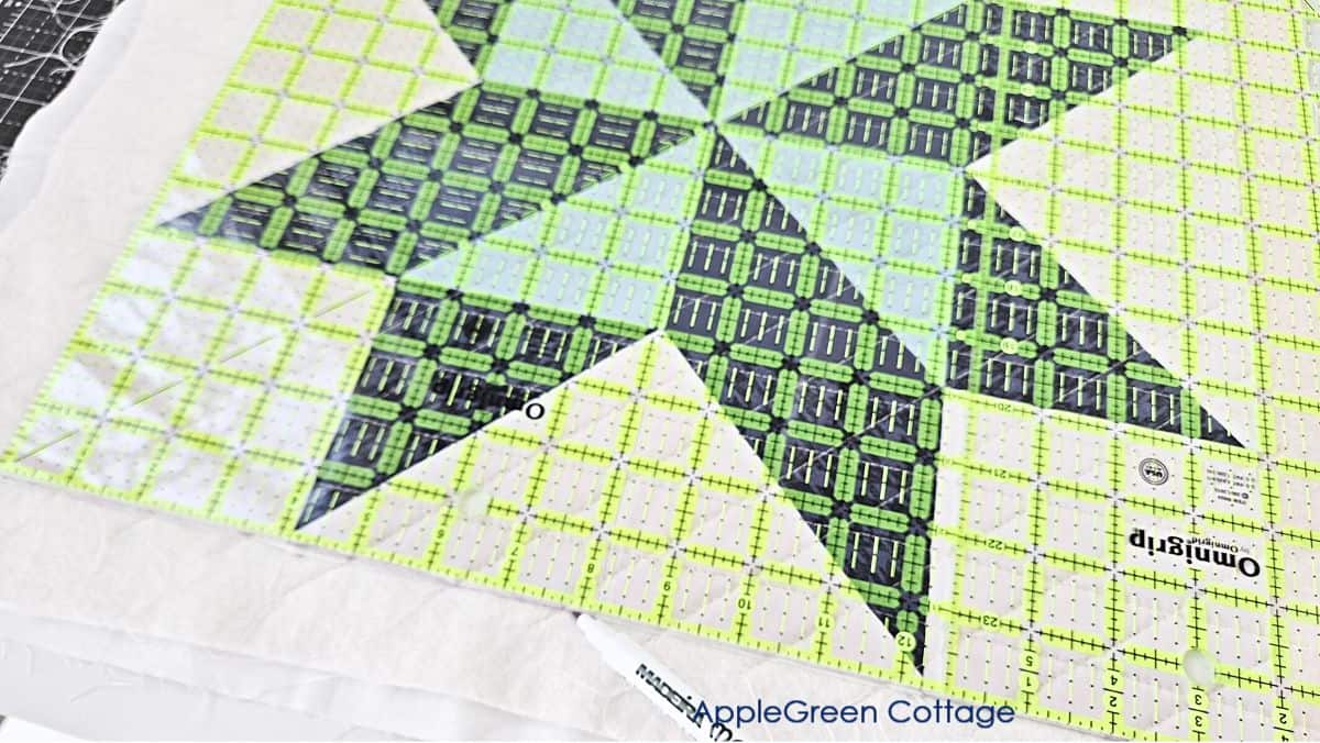 a mini quilt with a large omnigrip ruler placed on the edge to square up the quilt to size.