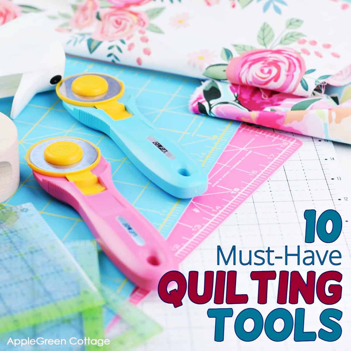pink rotary cutter and an aqua olfa rotary cutter placed on a white cutting mat next to a set of quiltign rulers and beautiful floral quilting cotton print