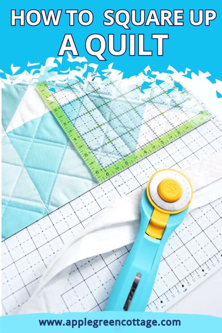 aqua rotary cutter on a square quilting ruler placed on a semi-finished quilt ready to be squared up