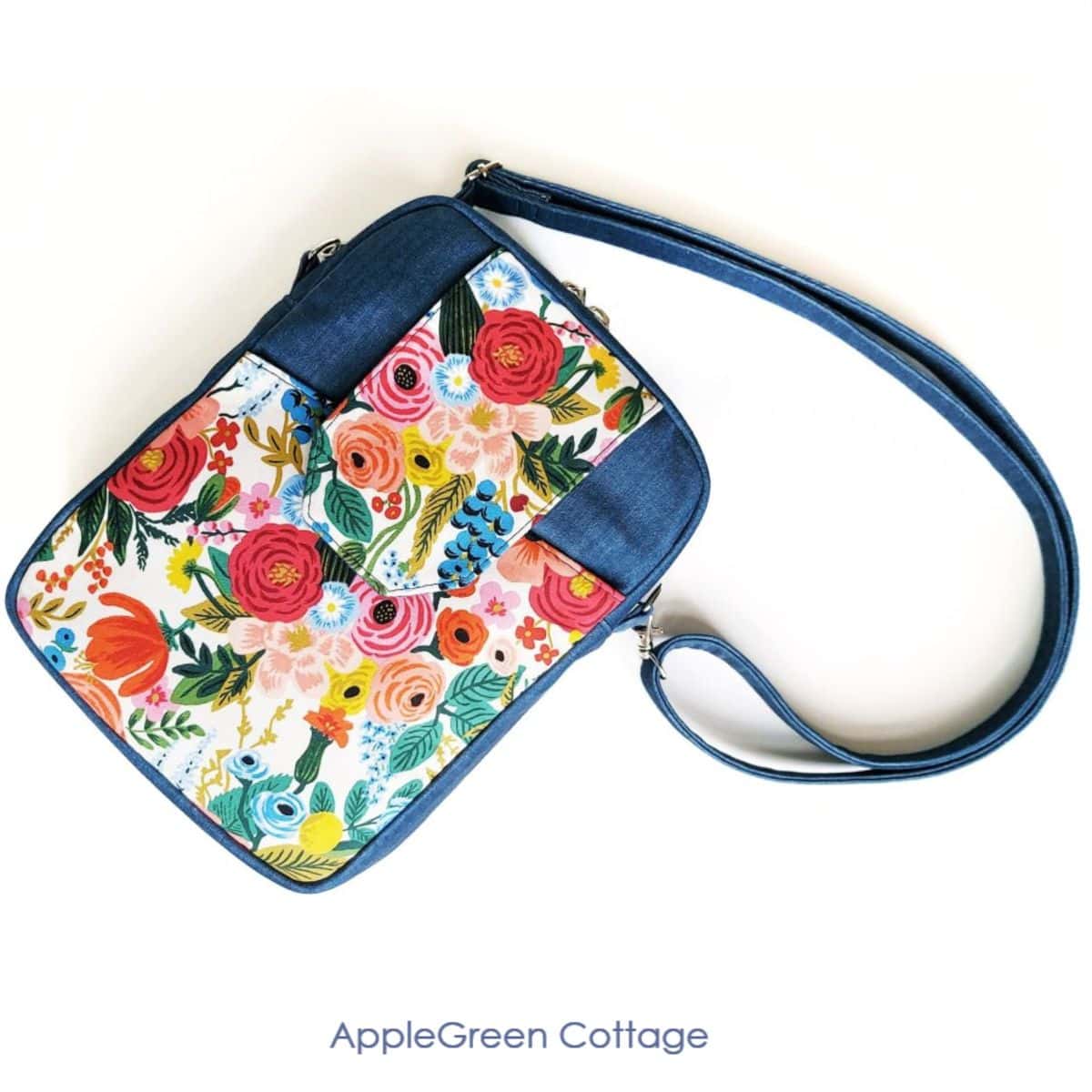 a finished handmade crossbody bag in deep blue and Rifle Paper floral print, with a flap pocket in the front and a crossbody strap attached