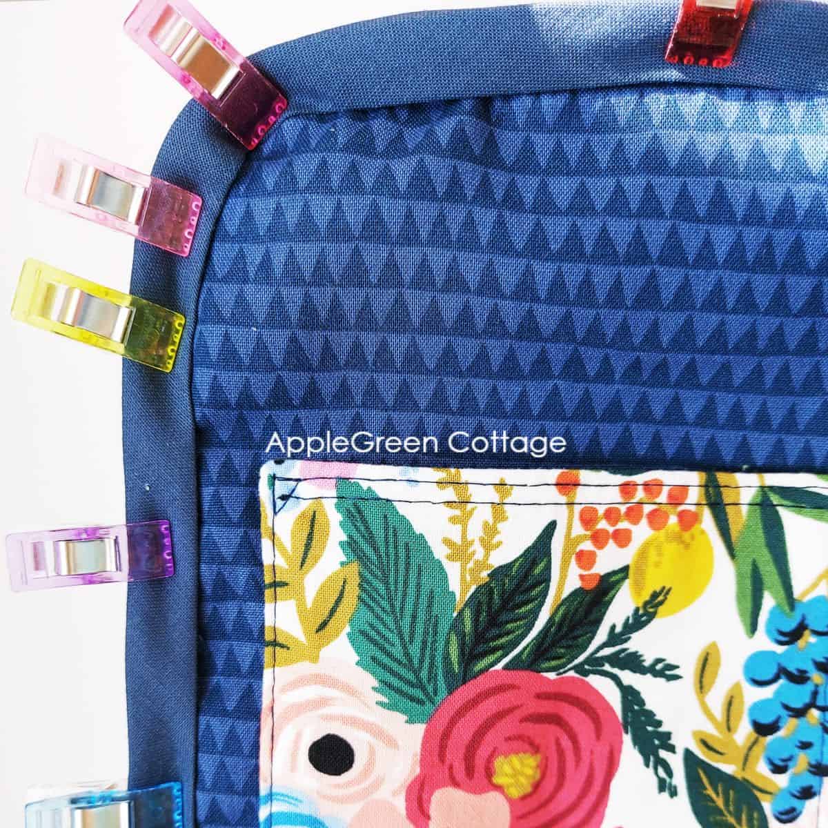 a closeup of a bag interior being finished with a strap of quilting cotton binding in deep blue, with several sewing clips attached