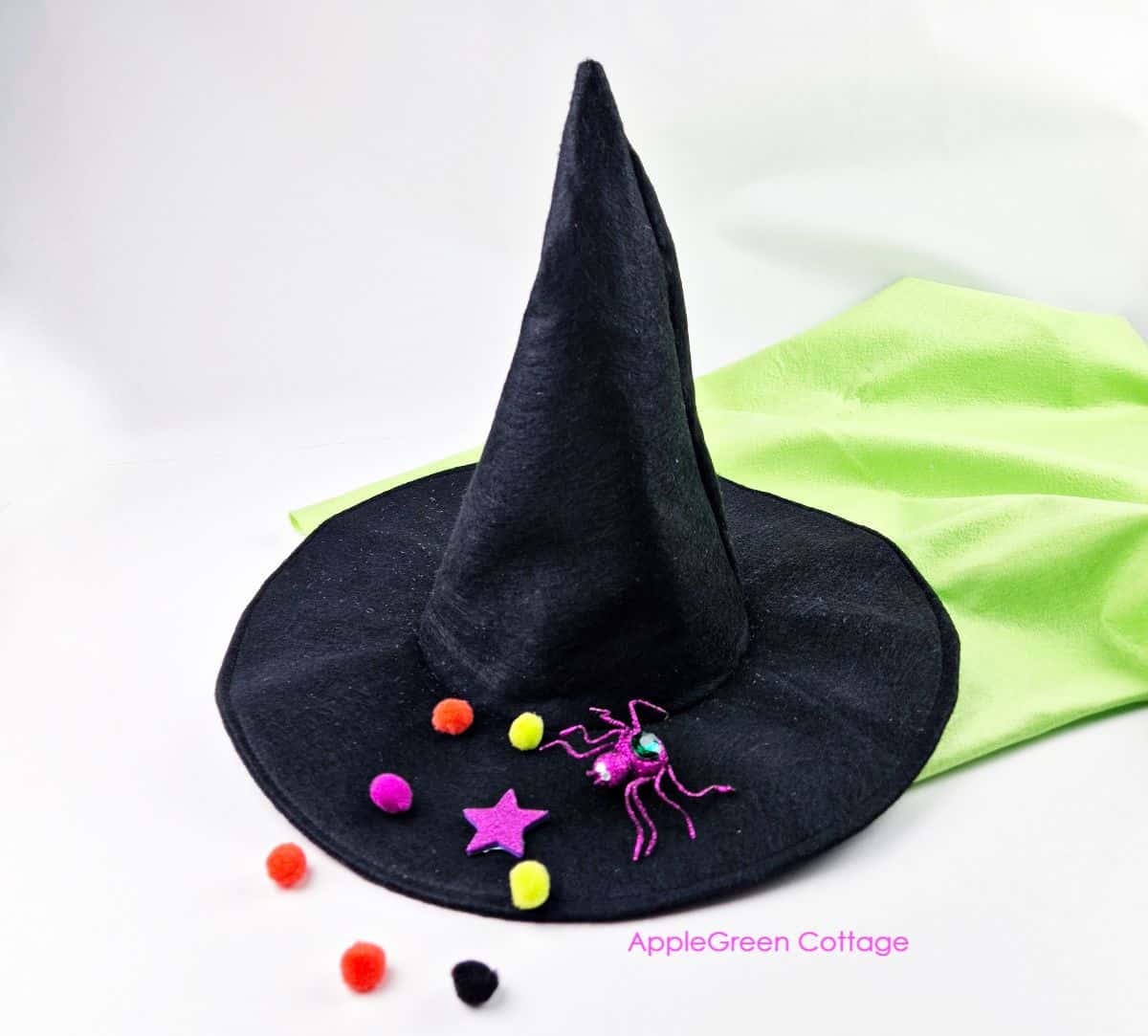 a black felt withch hat with purple and neon green decorations and pompoms as Halloween decor