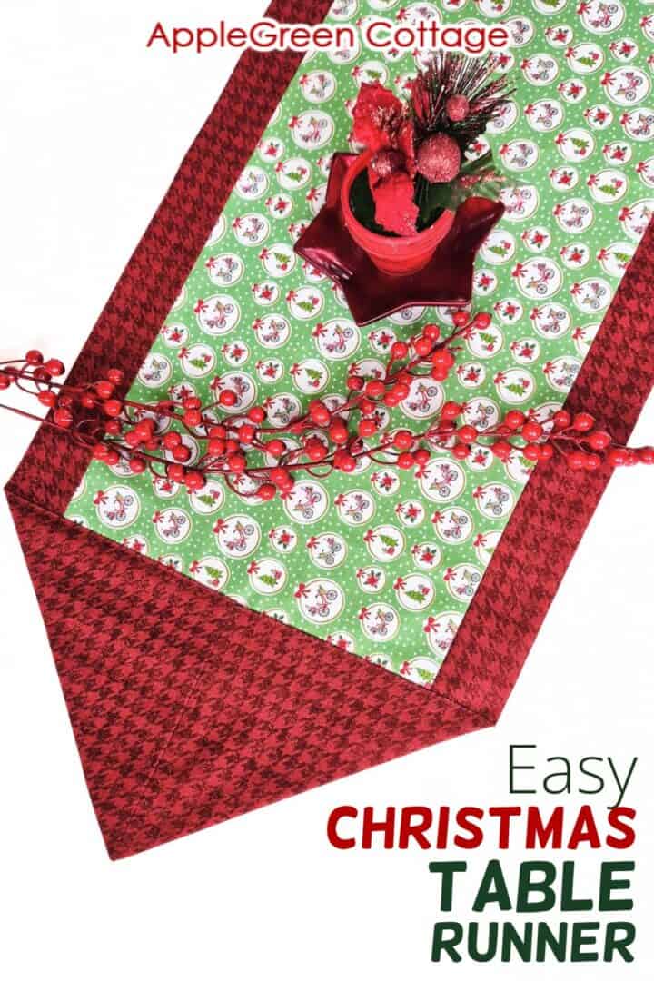 a finished fabric table runner sewn with two fabric pieces in Christmas prints, with a red glossy star-shaped plate on it and 2 stems of holly red berries