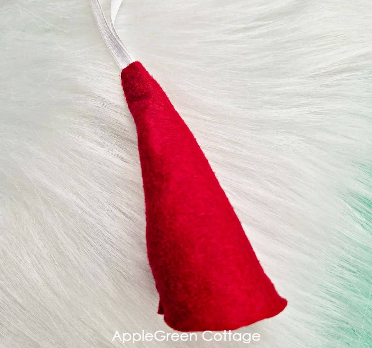 a finished tiny gnome hat in red felt with a faux fur background