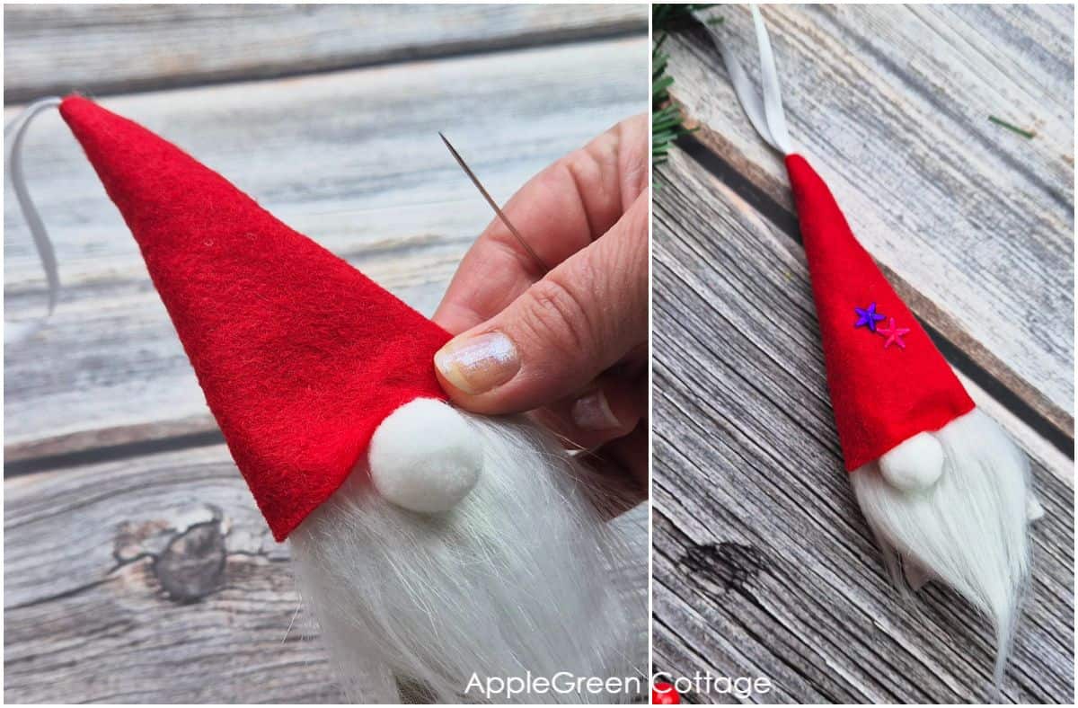 a hand with a sewing needle attaching a tiny gnome hat to the gnome head, on a wooden background