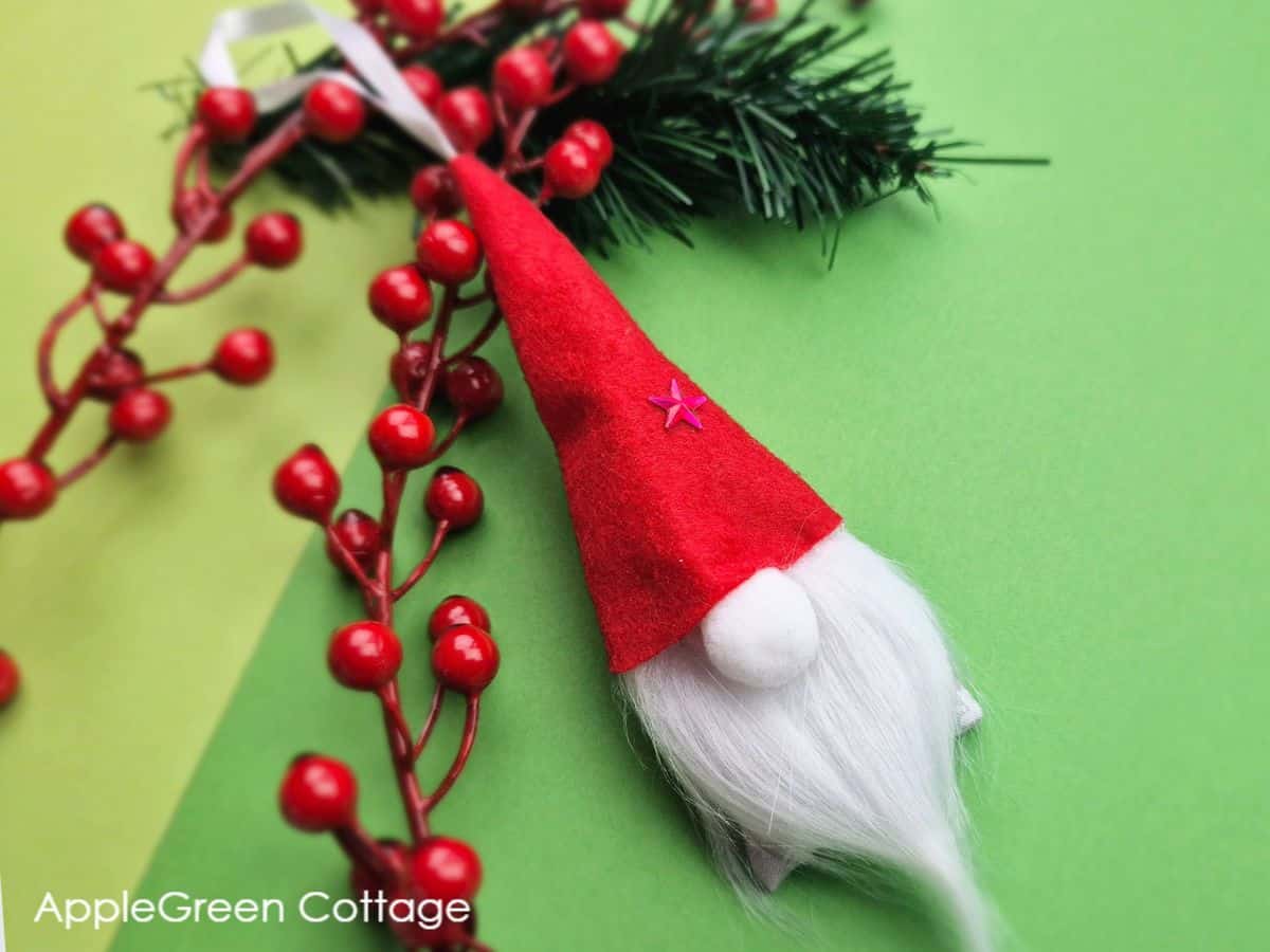 a finished handmade Christmas gnome ornament placed on a green background