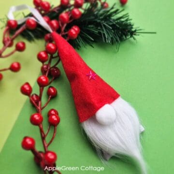 a finished handmade Christmas gnome ornament placed on holiday greenery