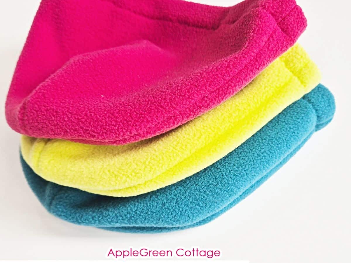 three finished fleece beanies in teal, hot pink and neon colors