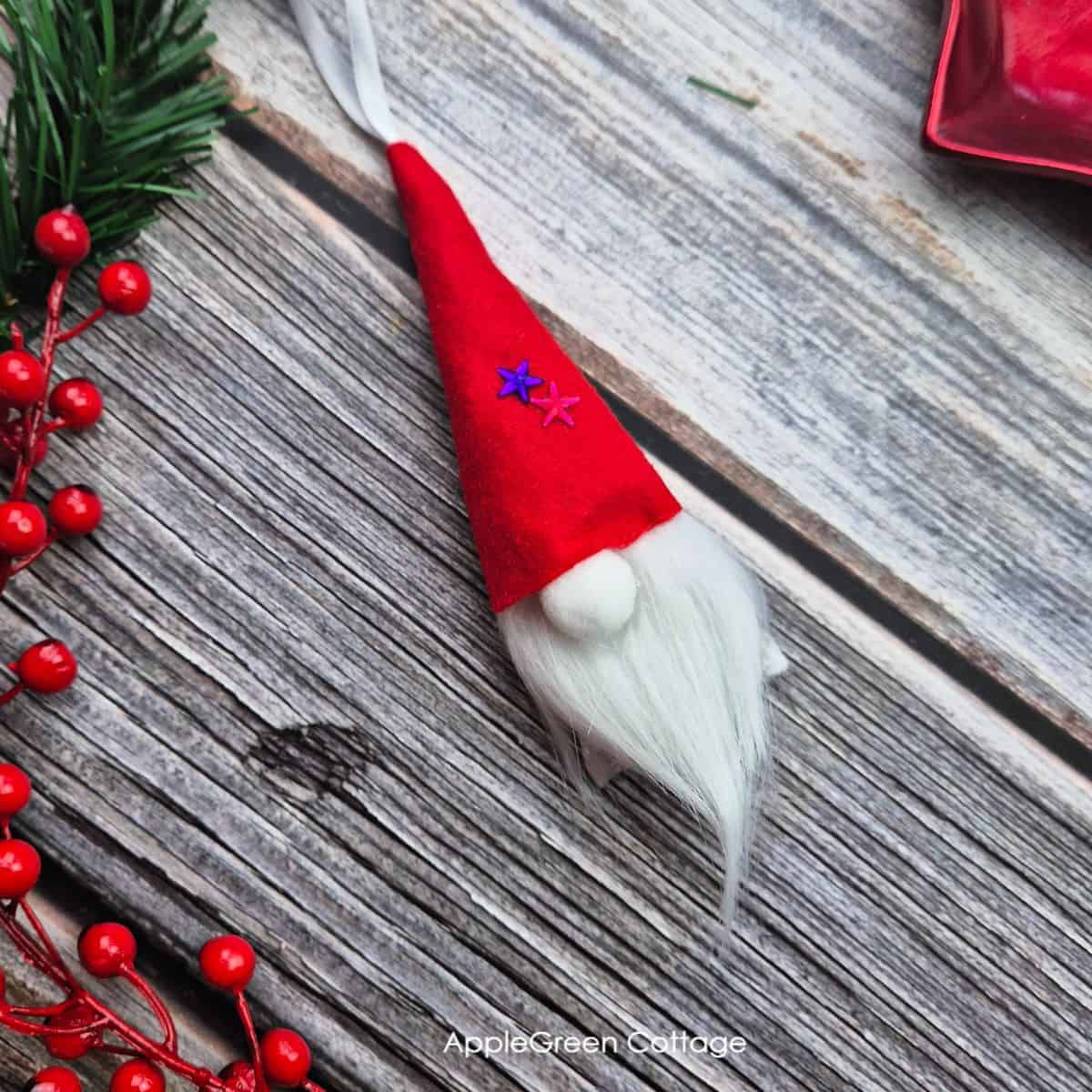 a finished handmade Christmas gnome ornament placed on a wooden background