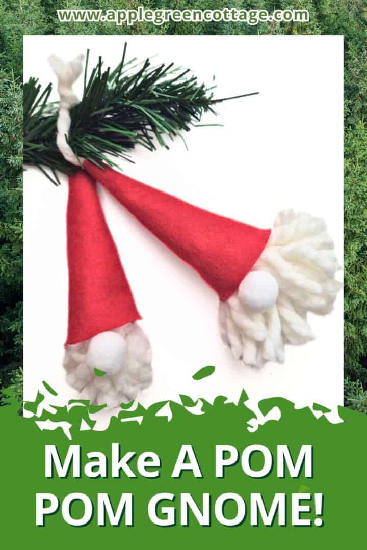 two homemade pompom gnome ornaments with red felt hats and white yarn heads with holiday spruce twigs