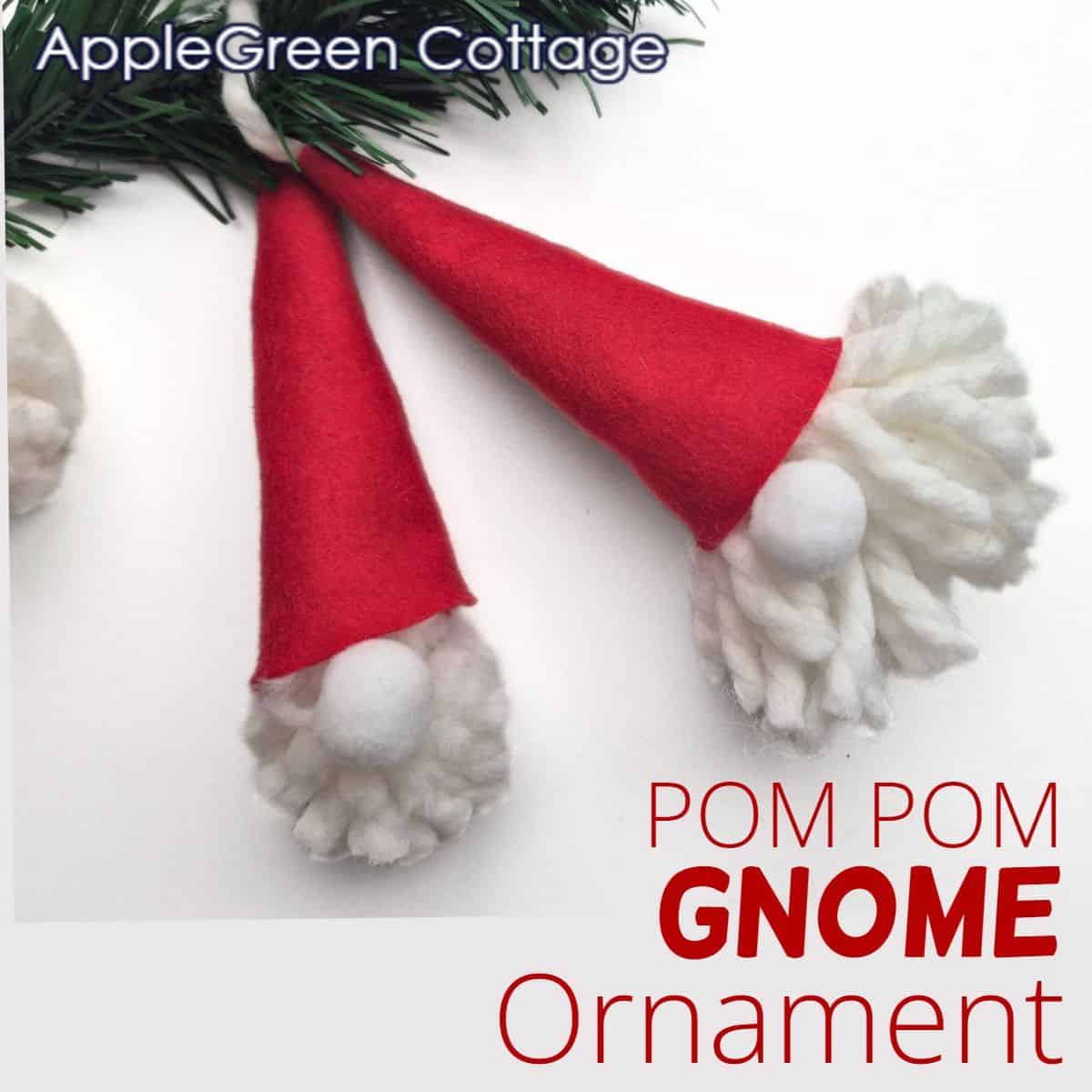 two homemade pompom gnome ornaments with red felt hats and white yarn heads with holiday decorations in green