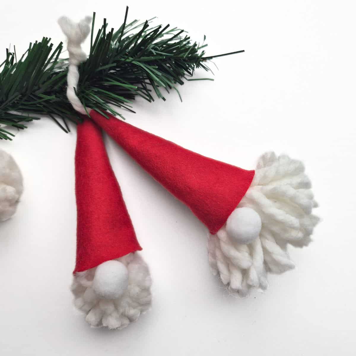two handmande gnomes made from a diy pompom and a red cap using a free gnome hat pattern