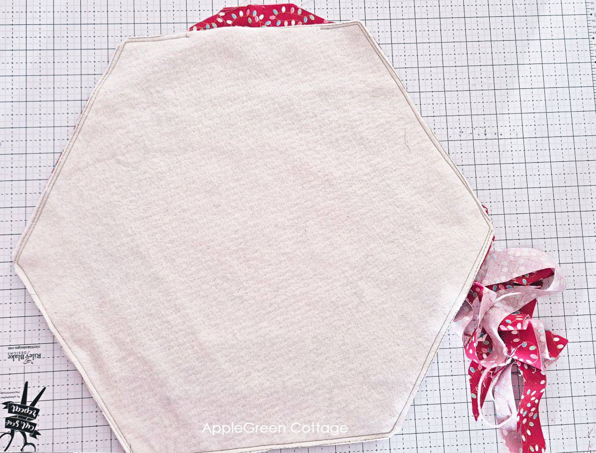 a hexagon-shaped piece of batting basted onto a hexagon quilt top