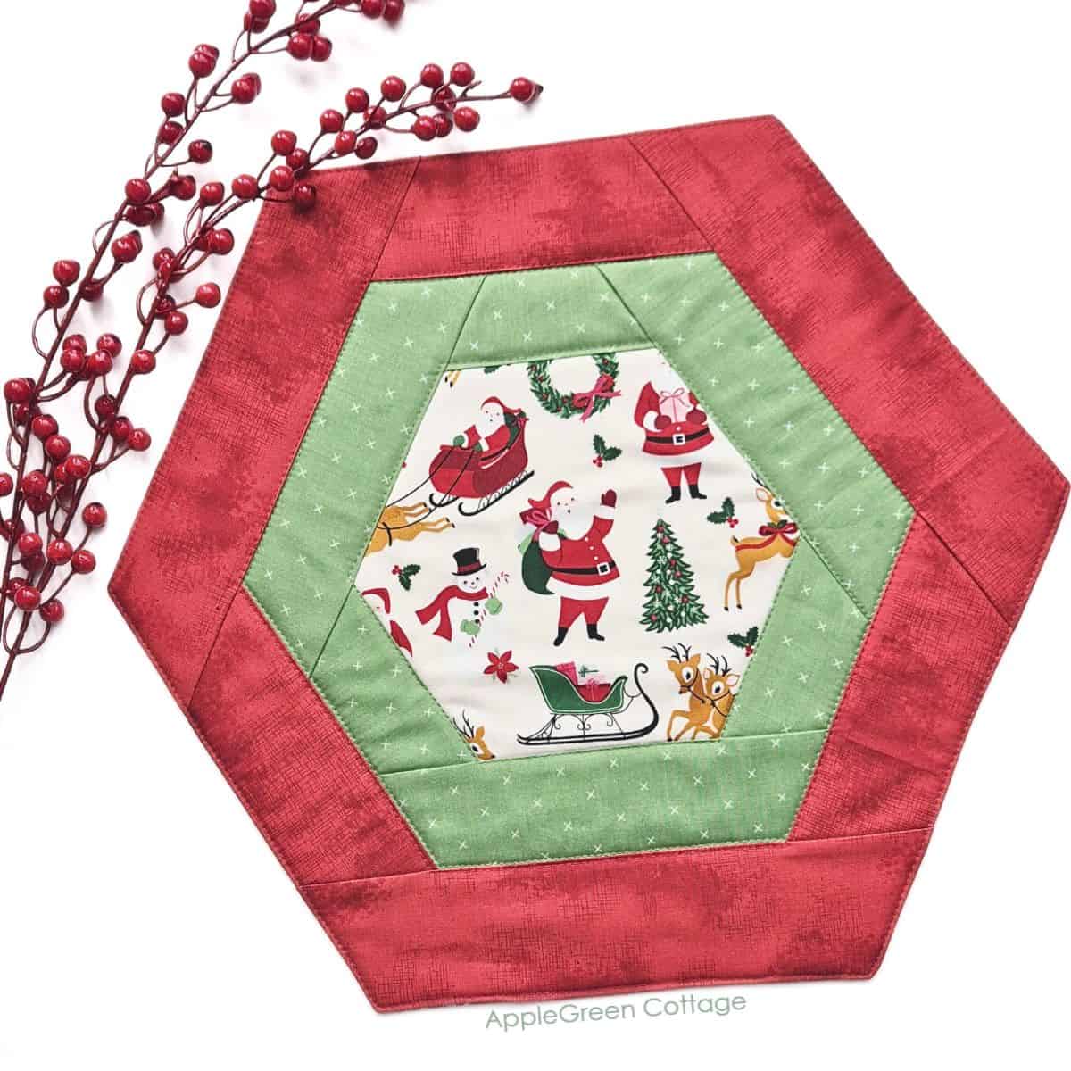 a pieced red hexagon table runner in holiday prints with a red poinsettia pot plant decoration