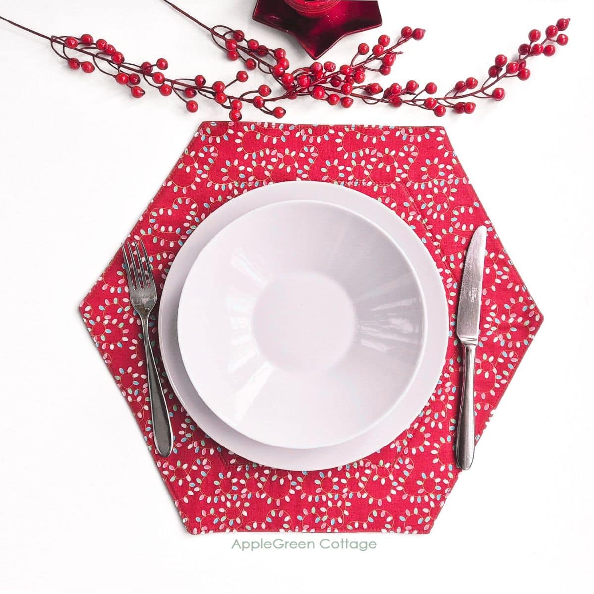 a finished handmade red holiday themed hexagon placemat runner with a plate and cutlery