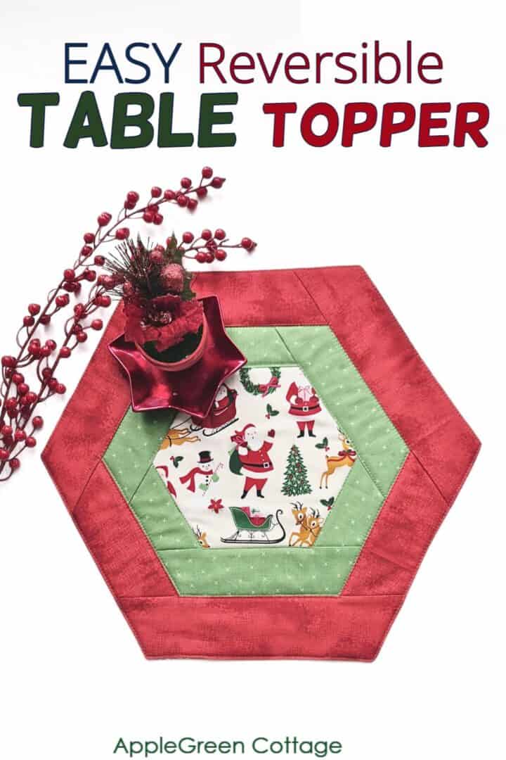 a pieced red hexagon table runner in holiday prints with a red poinsettia pot plant decoration